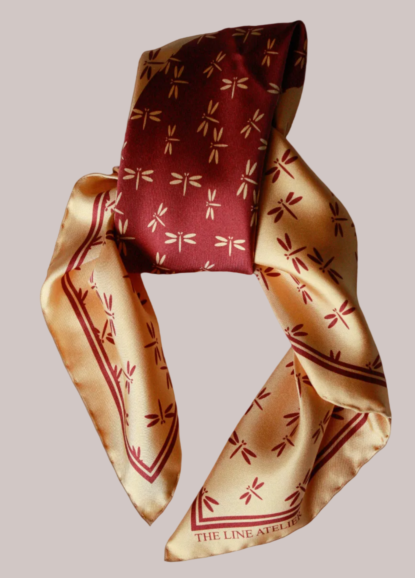 Red and gold patterned silk scarf on a beige background