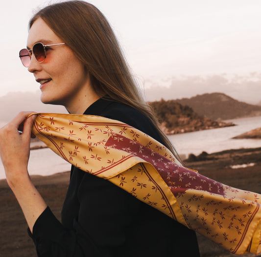 Woman wearing a patterned silk scarf with a scenic background