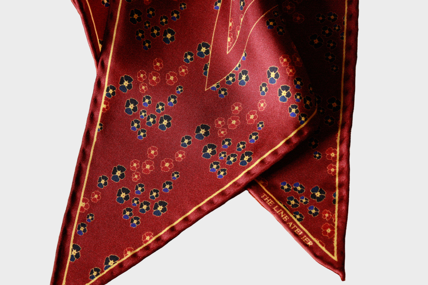 Red silk diamond scarf with floral pattern on a beige background