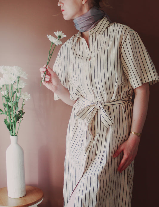 Model wearing Love Potion nr 9 Silk & Wool scarf by The Line Atelier holding flowers next to a vase on a table.