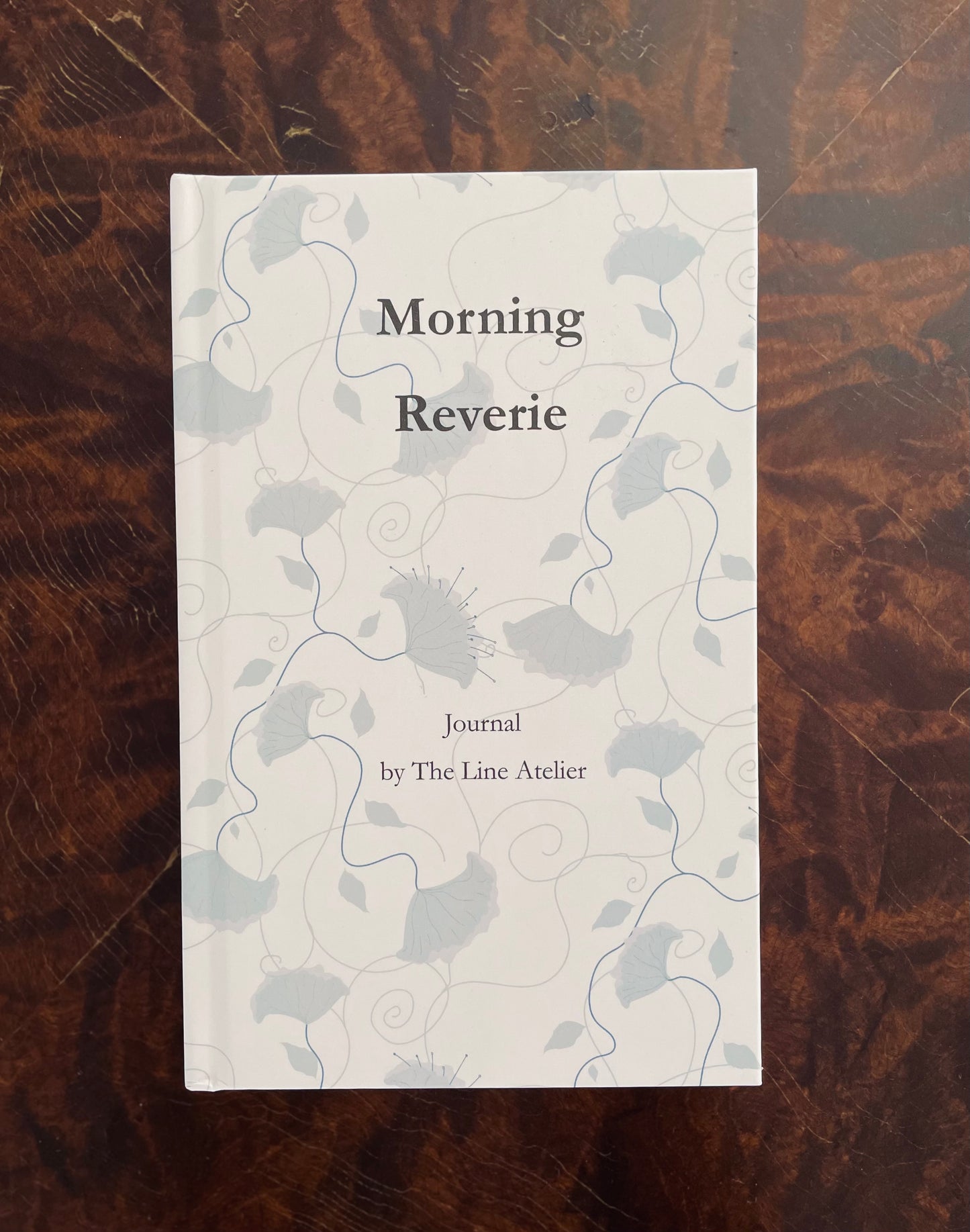 Journal titled 'Morning Reverie' by The Line Atelier on a wooden surface