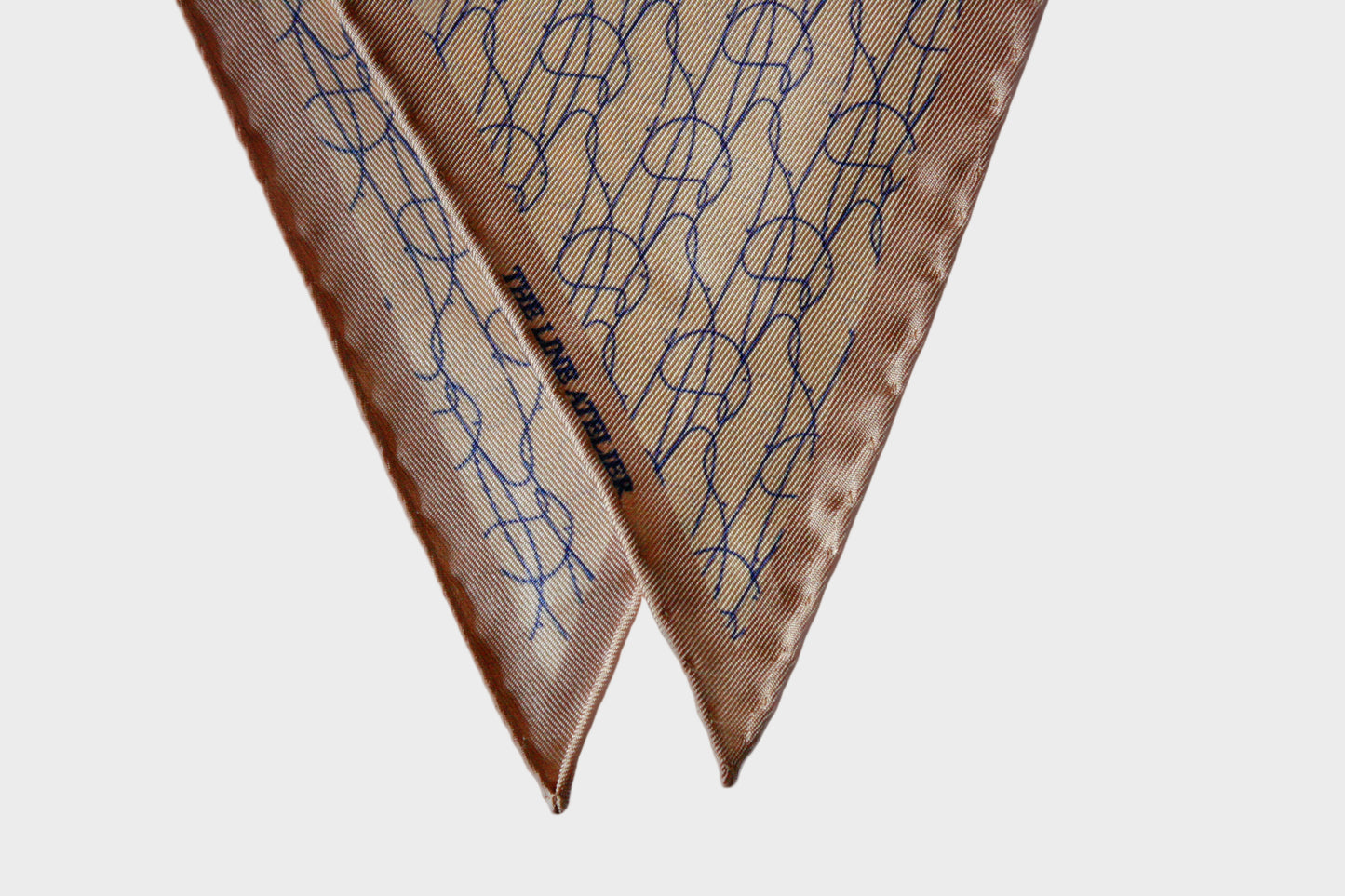 Rogue Of The Sands diamond silk scarf in tan silk with abstract blue pattern and hand rolled edges, detail photo, by The Line Atelier