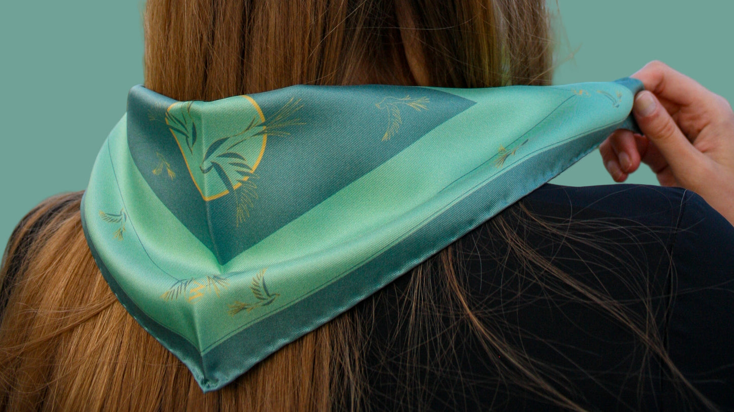 Model wearing Rogues Compass by The Line Atelier green silk scarf diamond size with swallows is gold lineart