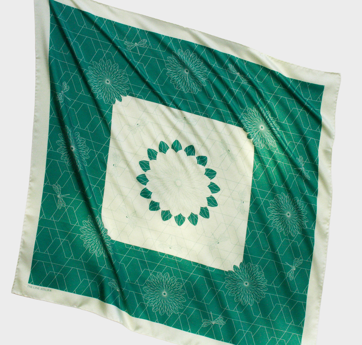 Green and white patterned silk scarf with a central design on a white background