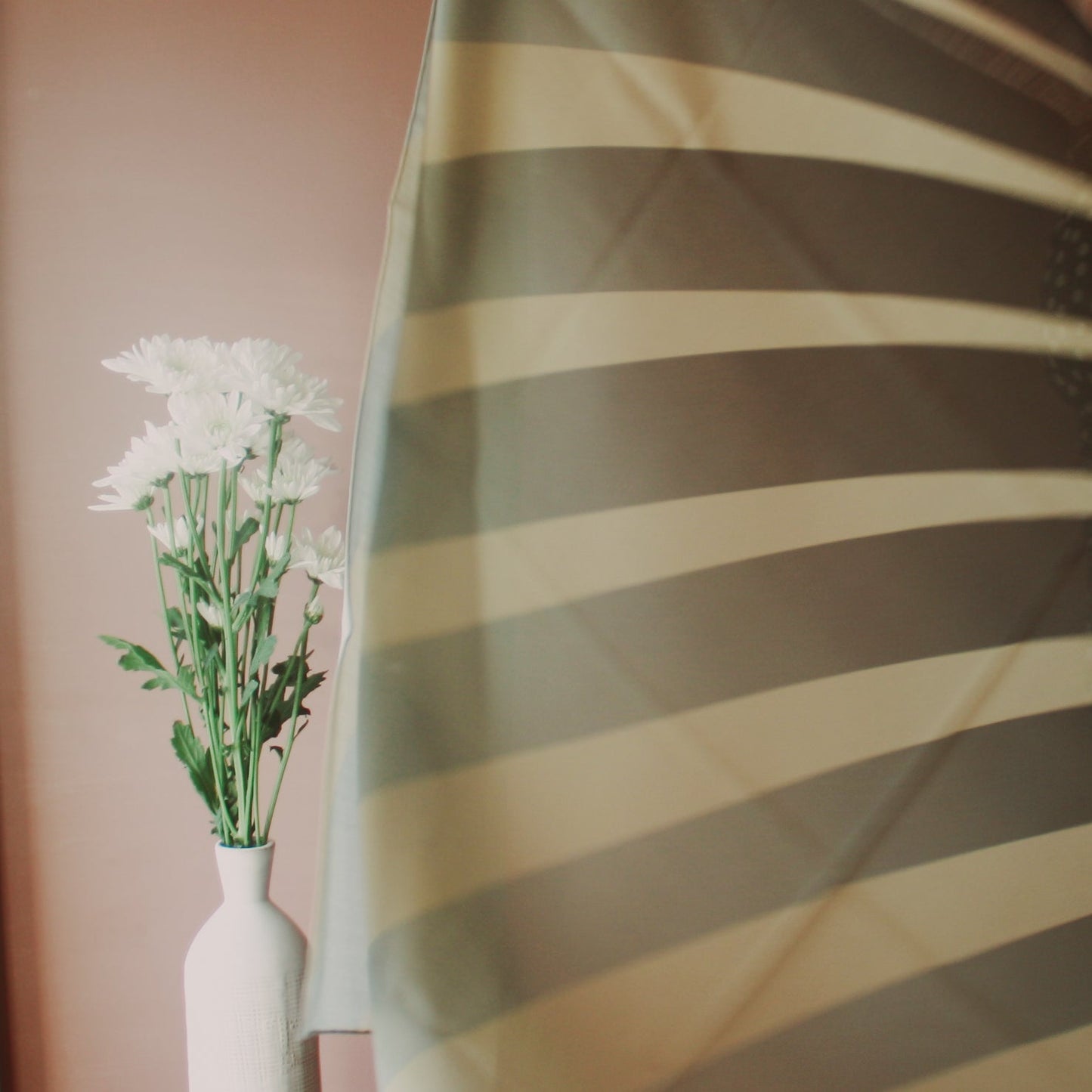White flowers in a vase with Willow Grove Wool & Silk Scarf by The Line Atelier in the foreground
