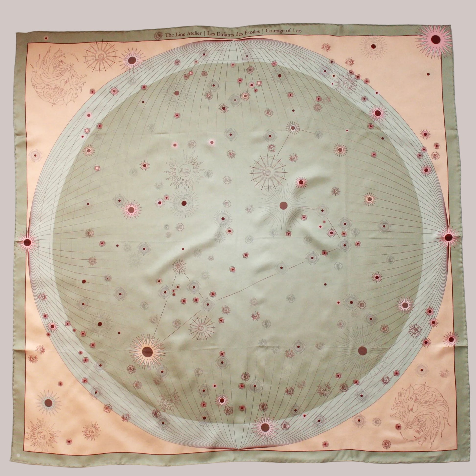 A square silk scarf featuring a celestial design with a large central pale green circle containing stars and the Leo constellation, surrounded by a peach-pink border and a muted sage green edge.