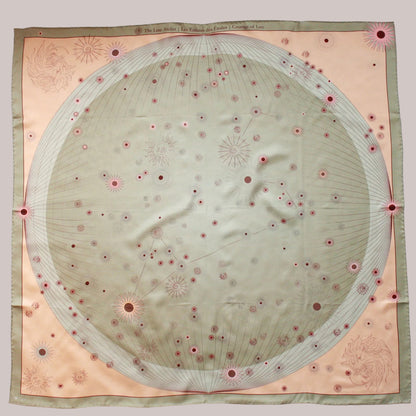 A square silk scarf featuring a celestial design with a large central pale green circle containing stars and the Leo constellation, surrounded by a peach-pink border and a muted sage green edge.