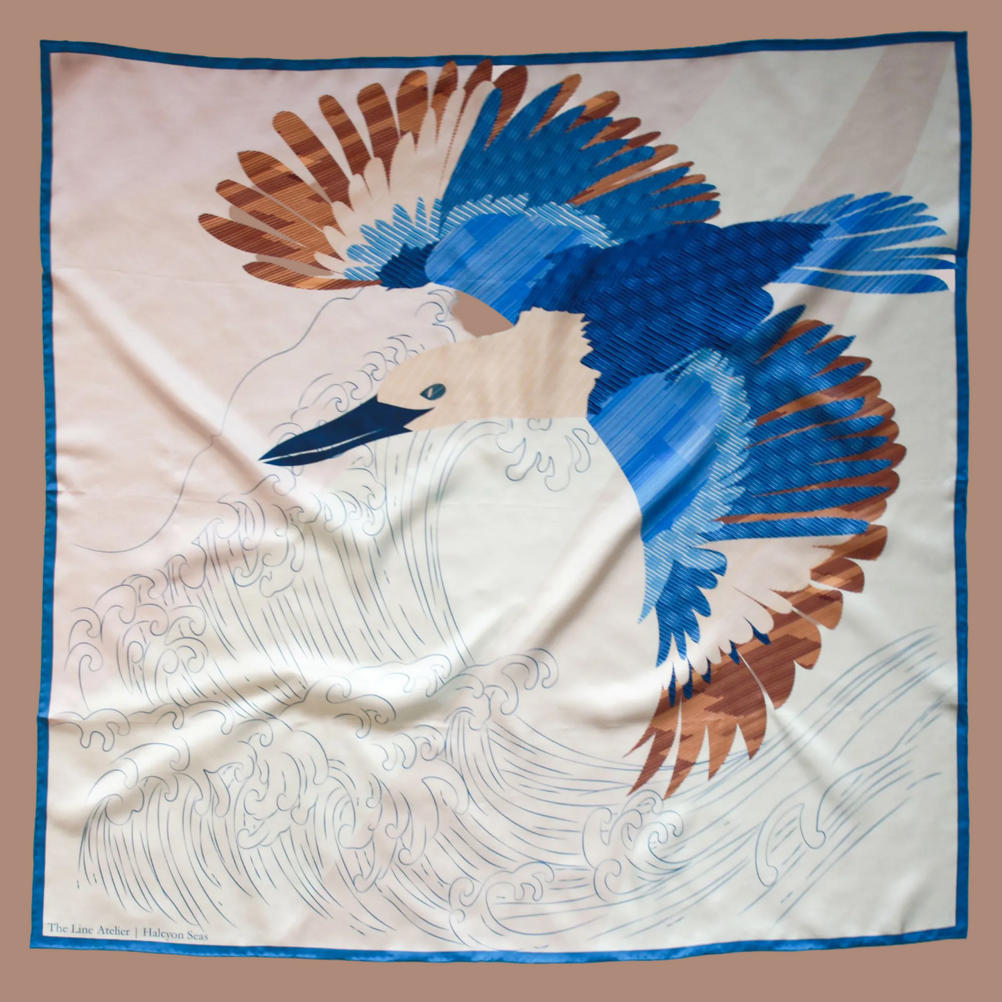 A square silk scarf featuring a stylized graphic print of a blue bird with brown and cream feather details flying over white waves, framed by a blue border.