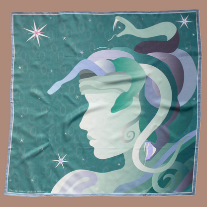 A square silk scarf featuring a stylized profile of Medusa's face in shades of mint green, lavender, and purple, with snakes and stars on a teal background. The scarf is displayed flat against a solid tan background.
