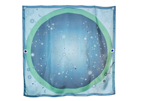 A square scarf featuring a celestial design with a light blue starry sky, a green ring, and the Cancer constellation patterns, hanging on a brown wall.