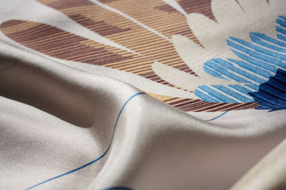 Close-up of a draped silk fabric with a printed pattern featuring blue, brown, beige, and white elements.