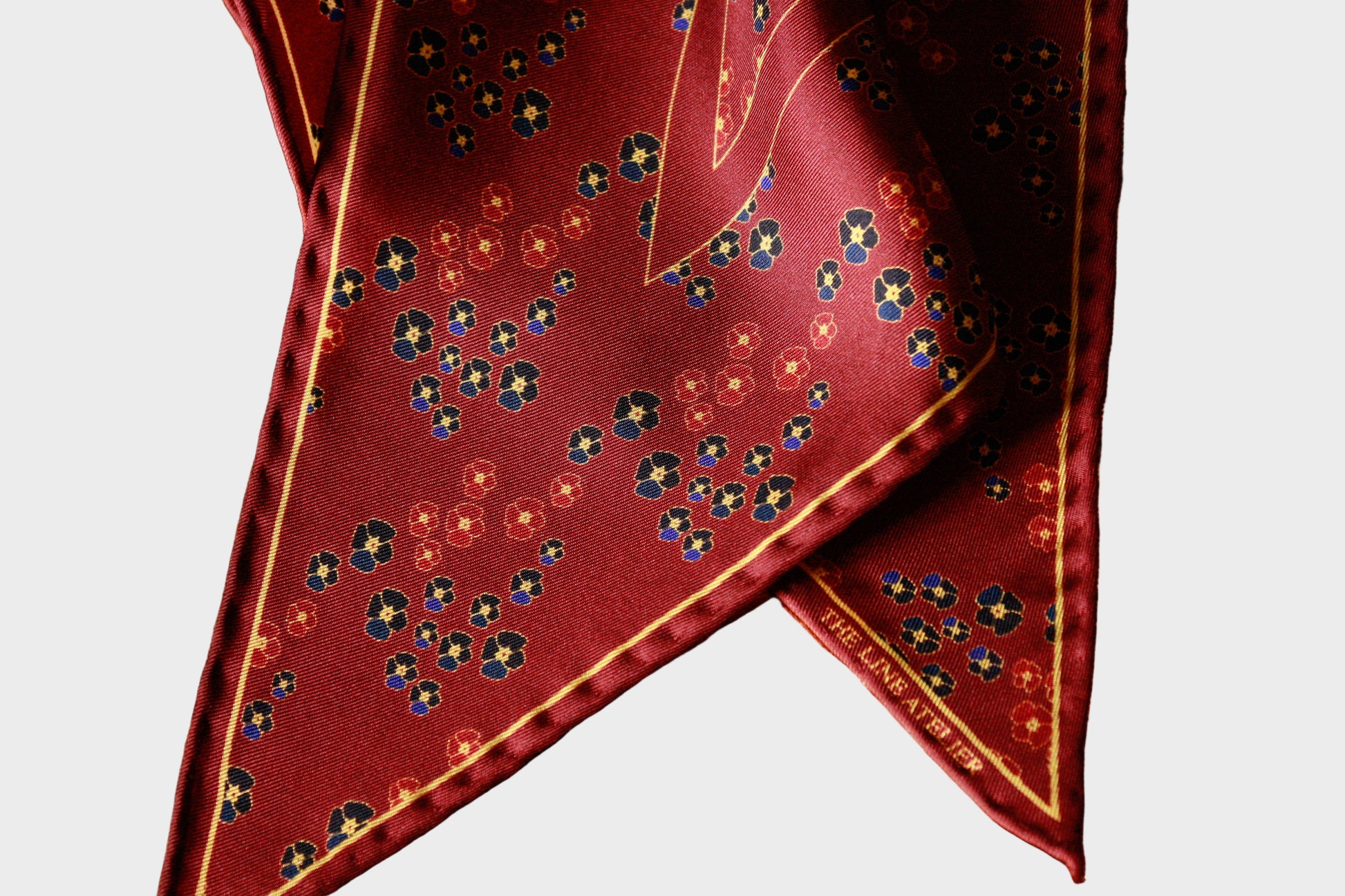 Red silk diamond scarf with floral pattern on a beige background