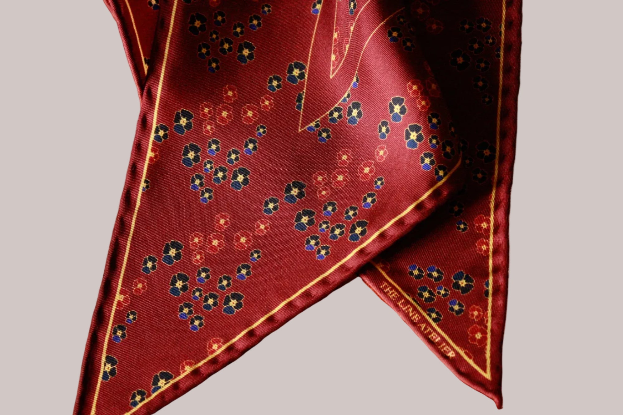 Red silk diamond scarf with floral pattern on a beige background