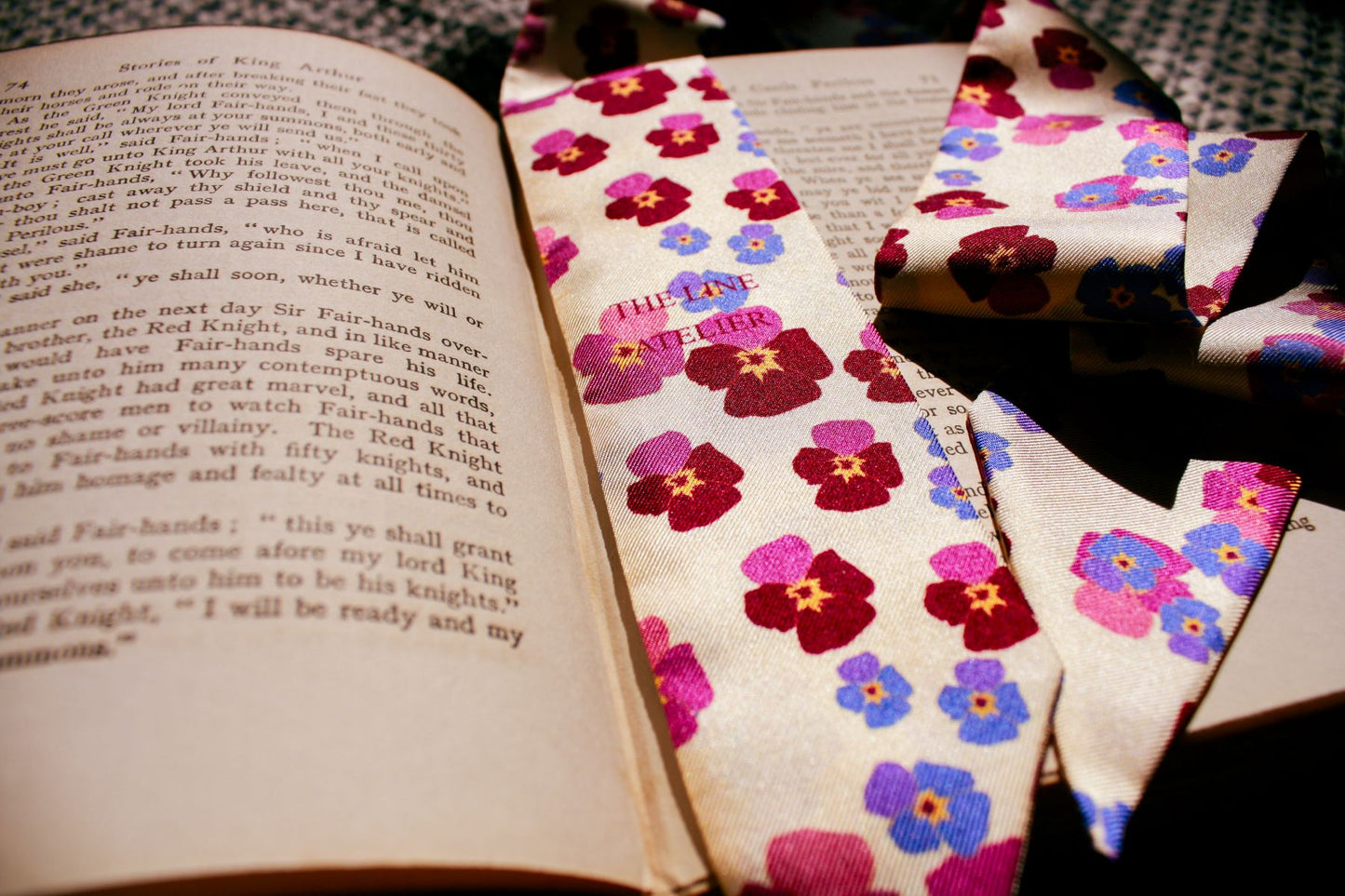 Hearts Ease silk twilly scarf laying over vintage book