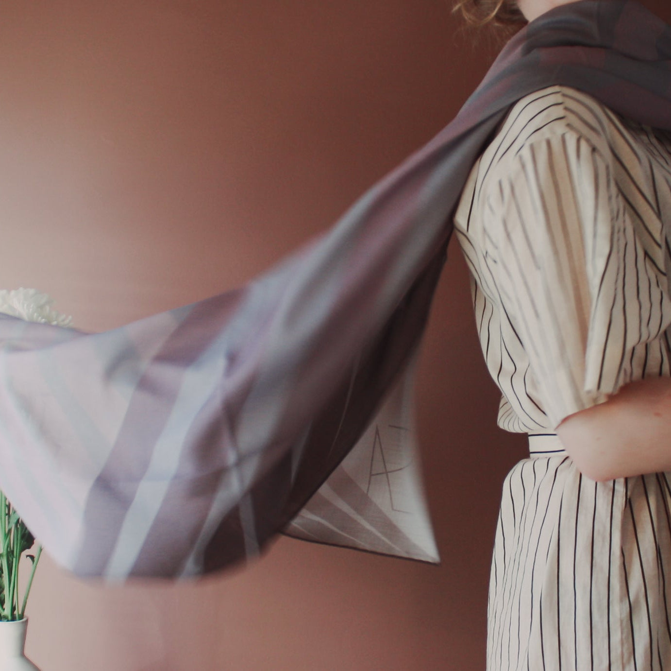 Person wearing a striped dress with Love Potion nr 9 Wool & Silk Scarf in a blurred indoor setting