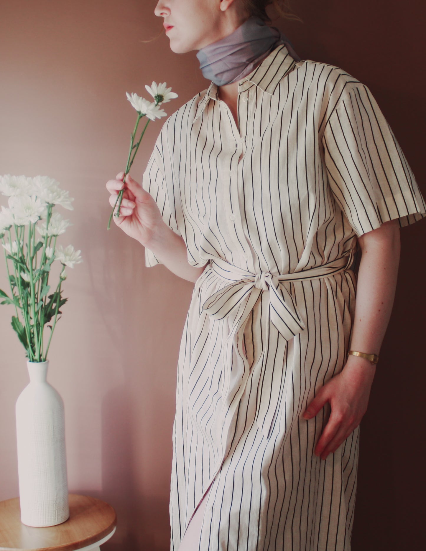 Model wearing Love Potion nr 9 Silk & Wool scarf by The Line Atelier  holding flowers next to a vase on a table.