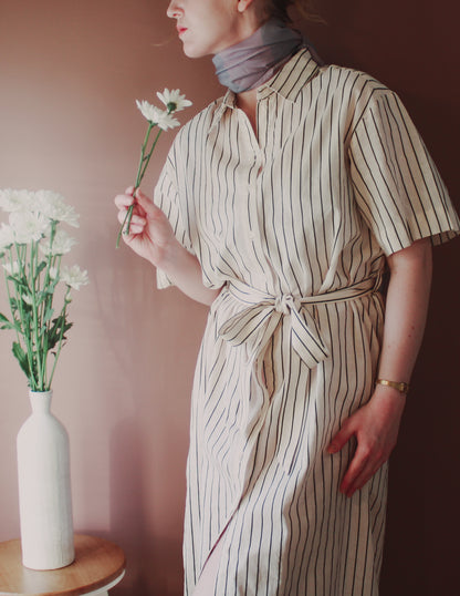 Model wearing Love Potion nr 9 Silk & Wool scarf by The Line Atelier  holding flowers next to a vase on a table.