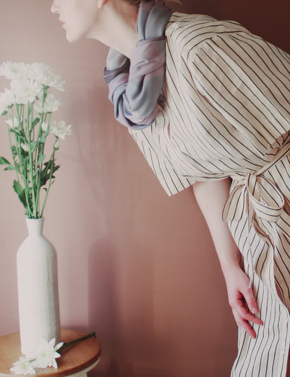 Model wearing Love Potion nr 9 Silk & Wool scarf by The Line Atelier with a white vase and flowers on a pink background