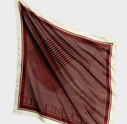 Brown and beige patterned silk scarf with 'The Line Atelier' label on a light gray background