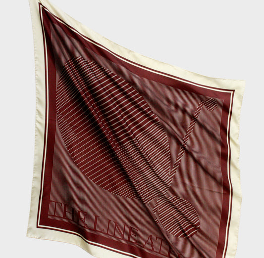 Brown and beige patterned silk scarf with 'The Line Atelier' label on a light gray background