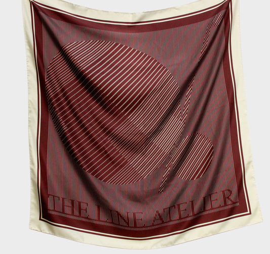 Maroon and beige scarf with 'The Line Atelier' branding on a light gray background