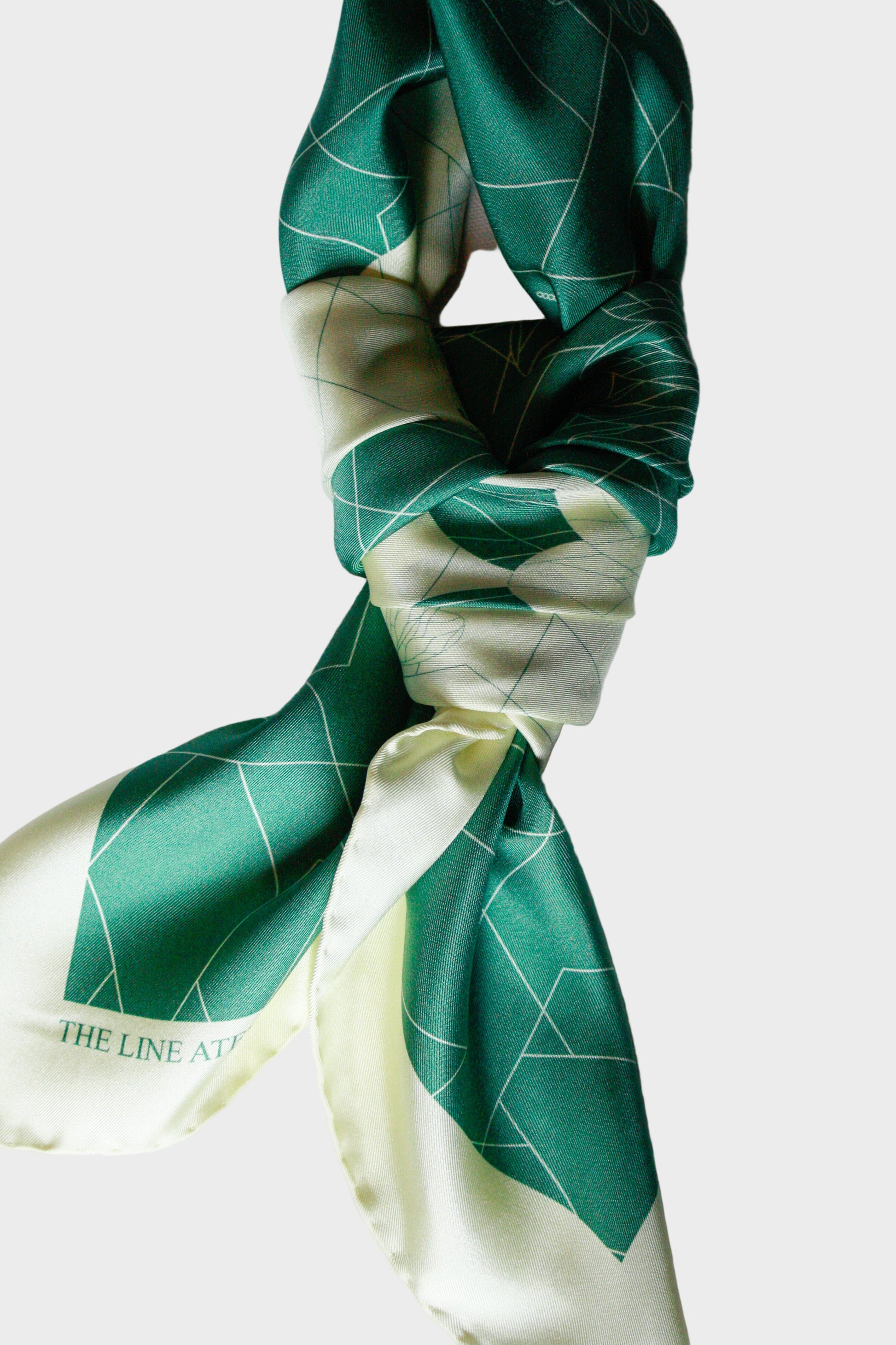 Green and white patterned silk scarf on a white background