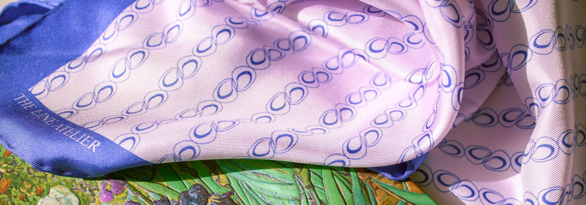 Folded silk scarf Wild Overture 60 cm purple and blue organic chain pattern on top of a Van Gogh painting notebook.